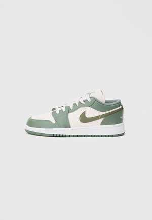 Baskets basses avec des panneaux en cuir blanc et vert atténué, logo Nike vert, lacets blancs et semelle blanche avec motif vert.