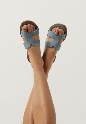 Blauwe stoffen sandalen met een open ontwerp, voorzien van uitsnijdingen en decoratieve studs, aangevuld met een bruine zool en strapaccenten.