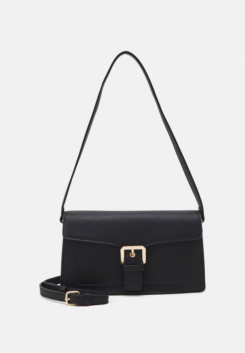 Sac d'épaule rectangulaire noir avec rabat et boucle dorée, avec une sangle supplémentaire réglable enroulée à la base sur fond blanc.