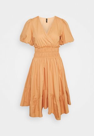 Robe couleur pêche avec un design portefeuille, manches bouffantes, taille élastique et jupe à volants. Tissu doux et léger avec une texture lisse.