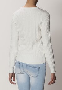 Witte gebreide trui met kabelpatroon, geribbelde manchetten en zoom. Zacht textuur, slim fit ontwerp en lange mouwen. Gezien vanuit de achterkant.