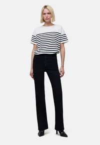 Wit en zwart gestreept T-shirt met korte mouwen, gecombineerd met zwarte, hooggetailleerde flare-broek met knopen aan de voorkant en een gladde textuur.