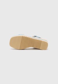 Woven blue and beige espadrille slide sandal with a ridged rubber sole and a metallic buckle accent. Textured surface offers grip.