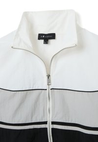 Witte en grijze jas met rits en zwarte accenten. Voorzien van een opstaande kraag, een ritssluiting over de hele lengte en een horizontaal gestreept patroon over het lichaam.