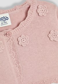Roza pletena cardigan sa okruglim izrezom, valovitim rubovima i tri aplikacije od heklanih cvjetova. Zatvaranje na gumbe sprijeda. Veličina 18-24m.