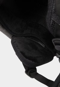 Zwart gewatteerd interieur met zachte, bontachtige structuur, mesh panelen, verstelbare bandjes en detail van een ritszak.