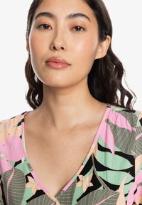 Robe florale avec des motifs roses et verts sur une base noire, dotée d'un décolleté en V et d'une texture de tissu douce.