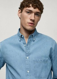 Camicia button-up azzurro chiaro con colletto, tasca frontale e una morbida texture in denim. Finitura liscia con dettagli di cucitura visibili.
