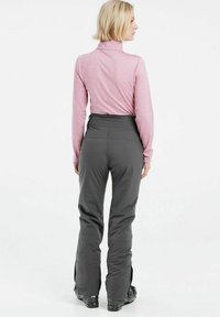 Gray ski pants with a high waistband, featuring a streamlined design and zippers at the ankles. Paired with a light pink long-sleeve top.
