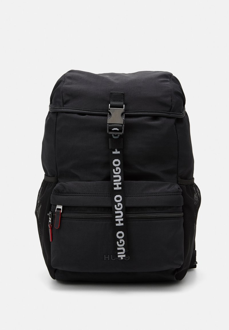 Zaino nero con patta superiore dotata di fibbia, tasca frontale con zip, tasche laterali in rete e tracolla con logo a marchio ripetuto.