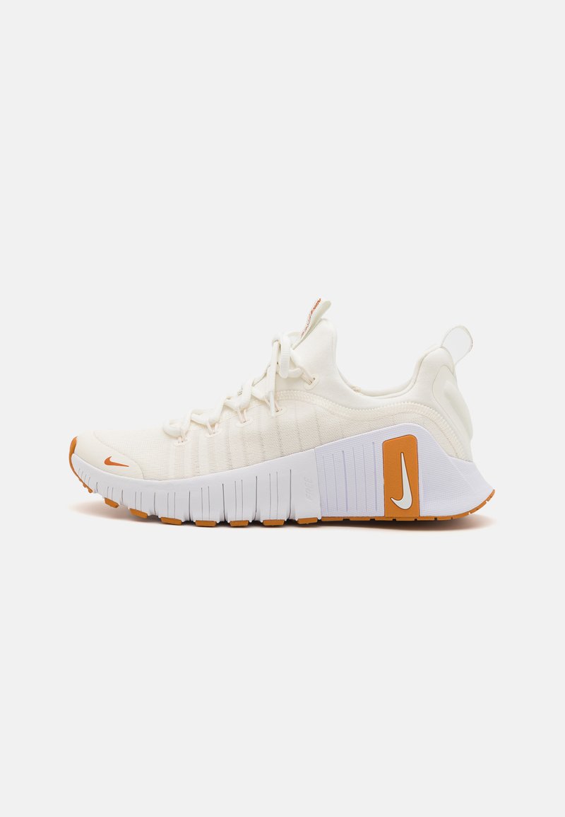 White athletic shoes with textured fabric upper and orange accents. Features a thick white sole with rubber grip and prominent branding.