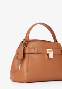 Borsa a tracolla in pelle marrone con una forma strutturata, manico superiore e accessori in oro. Presenta una chiusura e un dettaglio a linguetta sul manico. Texture liscia.