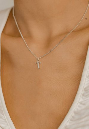 Silver chain necklace featuring a prominent T-shaped pendant adorned with small clear stones, showcasing a smooth metallic finish.