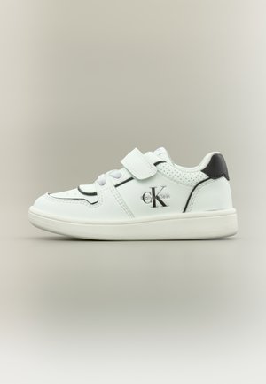 Scarpa da ginnastica bianca per bambini in pelle con dettaglio nero sul tallone, punta rotonda, lati traforati, lacci elastici e cinturino in Velcro regolabile.