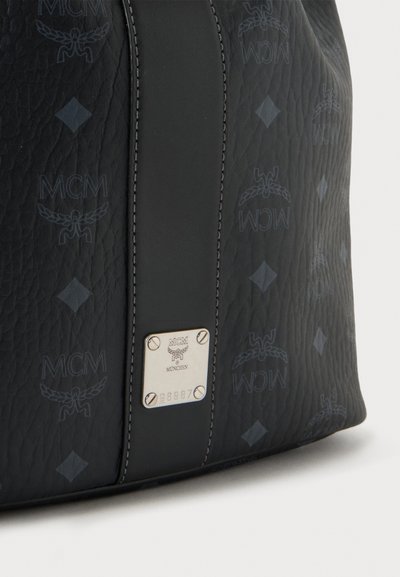 Sac en cuir noir texturé avec motif répétitif du logo MCM, bande centrale en cuir et petite plaque de marque argentée avec vis et numéro de série.