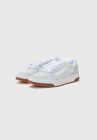 Adidași din suede albastru deschis cu sireturi albe, având perforații subtile, o dungi albă pe lateral și o talpă din cauciuc de culoare caramel.