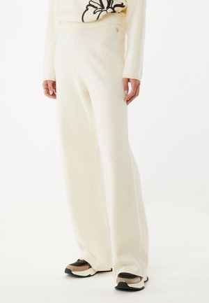 Witte, wijde broek gemaakt van zachte, gestructureerde stof; voorzien van een elastische tailleband en een klein gouden accentlogo.