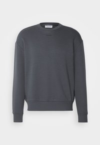 Sweat-shirt en coton gris avec un col rond, des poignets et un ourlet côtelés, et un logo subtil sur la poitrine. Présente une coupe décontractée.