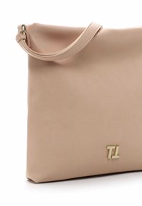 Borsa a mano in pelle beige con superficie liscia, caratterizzata da un logo "TL" in tono oro. Include una lunga tracolla per un facile trasporto.