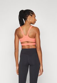 Rosa ribbet sports-bh med brede stropper og utskjæring bak, kombinert med høyt liv svarte leggings. Glatt tekstur, atletisk design.