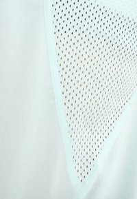 Gros plan sur un tissu blanc avec un panneau en maille triangulaire présentant de petites perforations pour la respirabilité et le contraste de texture.