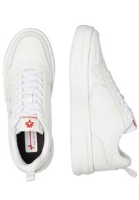 Zapatillas deportivas blancas con cordones, hechas de cuero suave, con una suela blanca gruesa, detalles de costura sutiles y un logo rojo en la lengüeta.