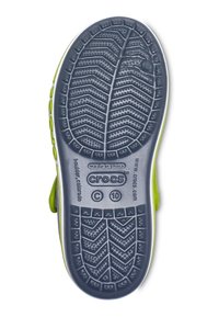 Semelle d'une chaussure Crocs verte et grise montrant le motif de la bande de roulement, taille 10, et le branding incluant "made in China" et "boulder, colorado."
