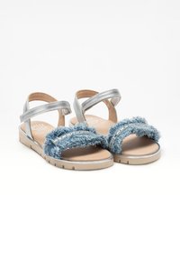 Sandali ispirati al denim blu con dettagli in tessuto sfilacciato, cinturini in argento, suola piatta beige e soletta imbottita per il comfort.