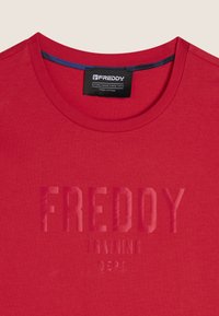 T-shirt in cotone rosso con scollo rotondo, caratterizzato da un logo testurizzato "FREDDY TRAINING DEPT." di colore contrastante. Tessuto morbido.