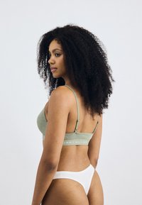 Groene katoenen bralette met dunne bandjes, met witte logo-tekst. Gecombineerd met een witte low-rise thong, een gladde textuur en een eenvoudig ontwerp.