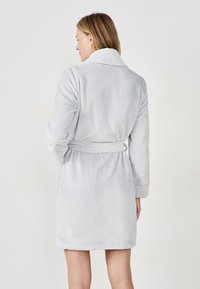 Accappatoio in pile grigio con colletto a scialle, maniche lunghe, vita regolabile e superficie morbida e strutturata.