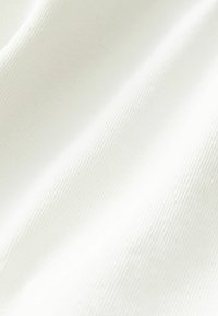 Tessuto di cotone color avorio con una sottile trama a coste. La superficie appare liscia e morbida, mettendo in risalto dolci pieghe e crepe.