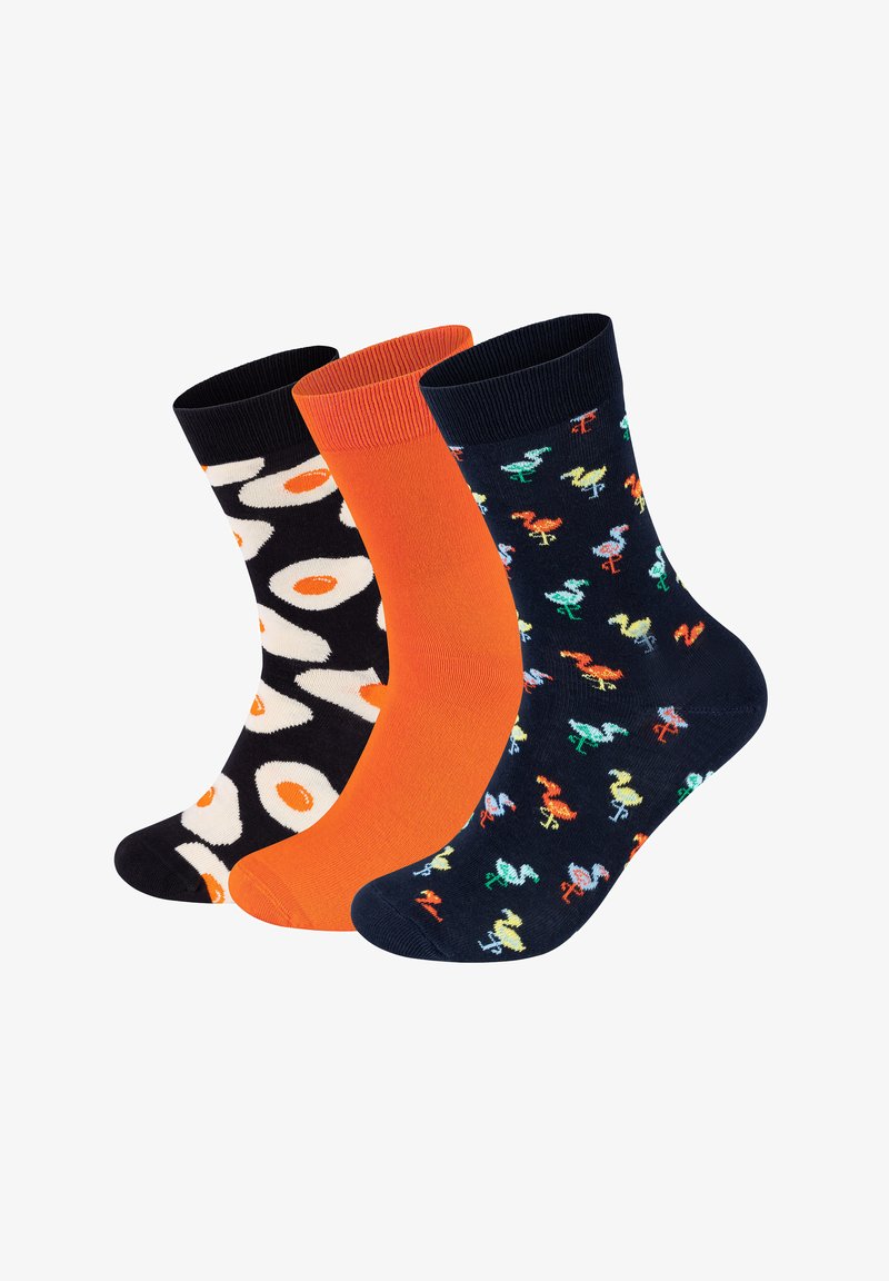 Trzy pary skarpetek: jedna czarna z białymi jajkami, jedna jaskrawa pomarańczowa, a jedna granatowa z kolorowymi wzorami flamingów, z prążkowanymi mankietami.