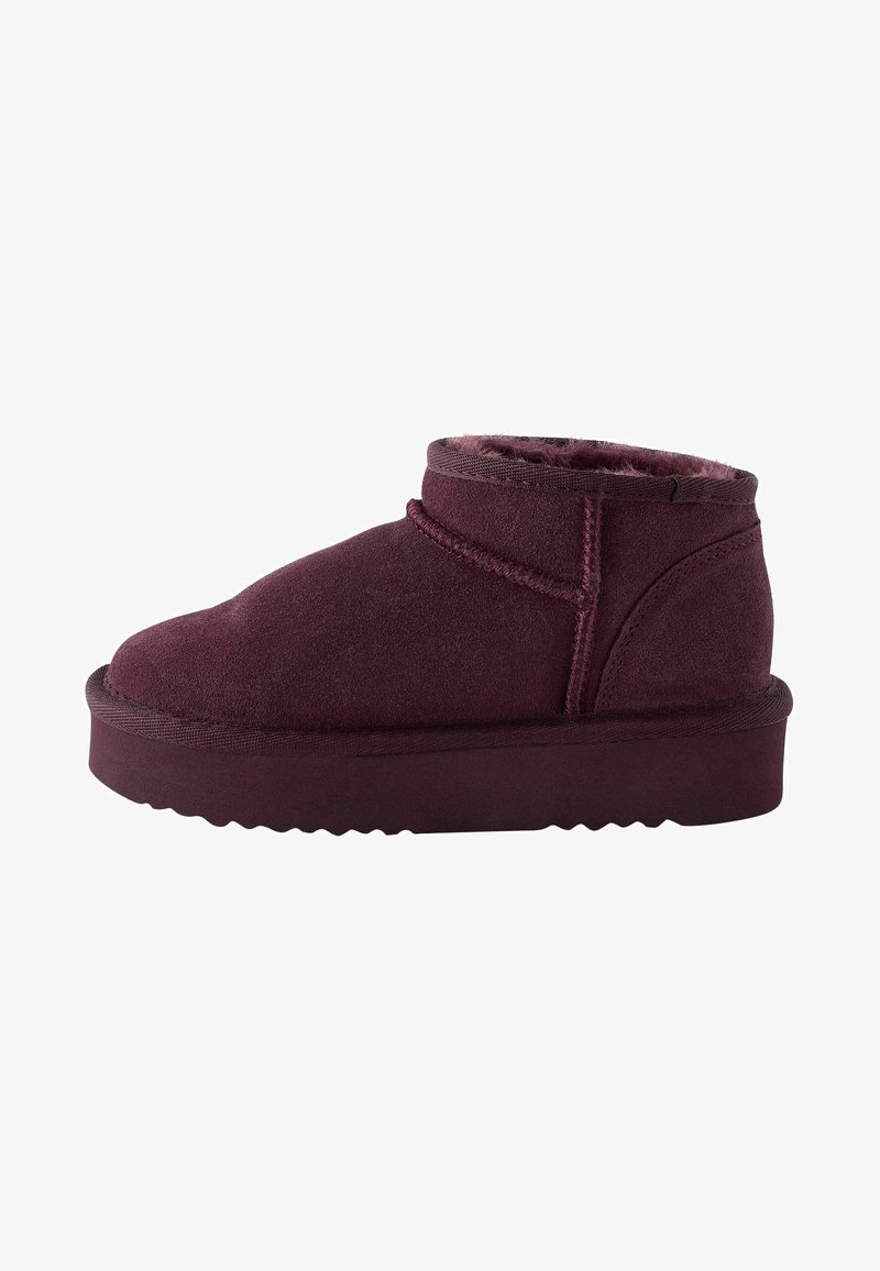 Burgundy ankle boots made of suede, featuring a rounded toe, soft lining, and a thick, textured rubber sole with a zigzag pattern.