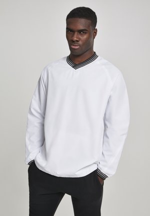 Hvid pullover med V-hals og sortstribet krave. Har lange ærmer og et afslappet snit. Glat tekstur, let stof.
