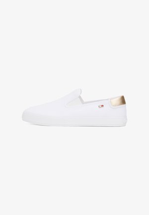 Witte instapsneaker met gouden hielstuk, klein vlaglogo aan de zijkant en dikke witte rubberen zool, zijaanzicht.
