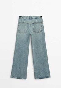 Jean large en denim bleu clair vu de dos avec deux poches carrées et des passants de ceinture sur fond blanc.