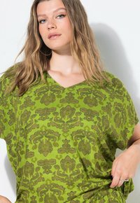 Blusa verde a fantasia con scollo a V in tessuto leggero, caratterizzata da un motivo floreale in verde scuro, con maniche corte e una vestibilità comoda.