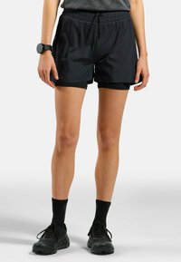 Zwarte sportshorts met een elastische tailleband, fijne textuur, binnenvoering en een losse pasvorm, gecombineerd met zwarte schoenen en sokken.