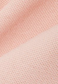 Gros plan de deux pièces de tissu rose texturé montrant des motifs de tricot distincts et des plis de matière douce.