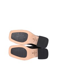 Chaussures noires en cuir avec une finition lisse, dotées d'un bout carré, d'une semelle plate et d'un talon en caoutchouc texturé. Logo embossé sur la semelle intérieure.