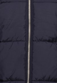 Chaqueta tipo puff en azul marino con un zipper vertical plateado. Presenta secciones acolchadas y un acabado suave y brillante.