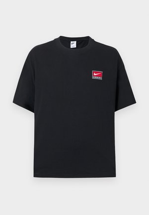 Sort Nike-t-skjorte med korte ermer og rund hals, med en liten rød og hvit Nike-logo på venstre bryst.