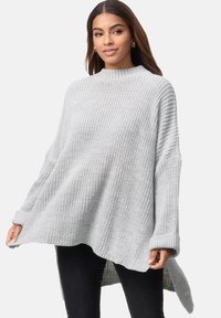 Hellgrauer Strickpullover mit hohem Kragen, weiten Ärmeln und gerundetem Saum, der ein strukturiertes Muster und eine lockere Passform aufweist.
