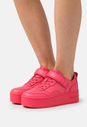 Bright pink platform sneakers featuring a smooth, synthetic upper, lace-up and Velcro strap closure, with textured outsole for grip.
