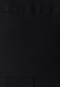 Zwarte stof met een diagonaal weefpatroon, een gladde textuur met een lichte glans en zichtbare stiklijnen langs de randen.