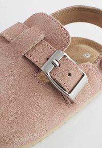 Chaussure en daim rose avec une boucle en métal argenté et des accents cousus. Design ouvert avec un dessus texturé et un intérieur doux.