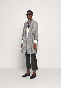 Grå rutigt oversized blazer med två knappar, en vit tröja, svarta lädercroppade byxor och svarta loafers. Färggarscarf som accent.