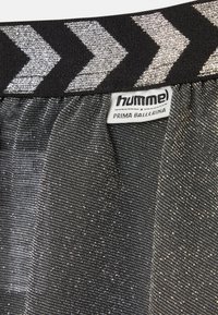 Svart kjol med silverfärgade chevronränder, textil med textur som innehåller metalltrådar och en märkning på midjebandet. Lämplig för balett eller dans.