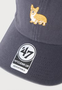 Καπέλο σε ναυτικό μπλε χρώμα από υφαντό ύφασμα, με χρυστό κεντητό σχέδιο κοργκί στο μπροστινό μέρος και μαύρη ετικέτα «47 Clean Up». Ρυθμιζόμενο λουράκι.